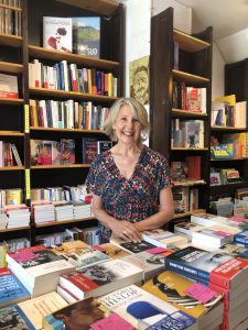 Nathalie Iris, souriante, dans sa librairie au milieu des livres